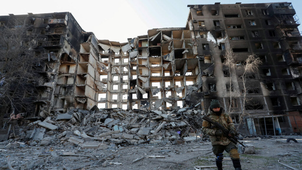 un soldado porrruso junto a un edificio destruido en Mariupol